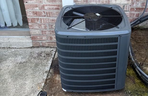 New air conditioning condenser set beside a brick home