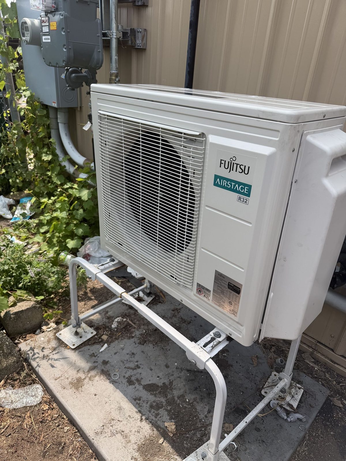 Fujitsu mini split outdoor unit mounted on a metal stand outside the office