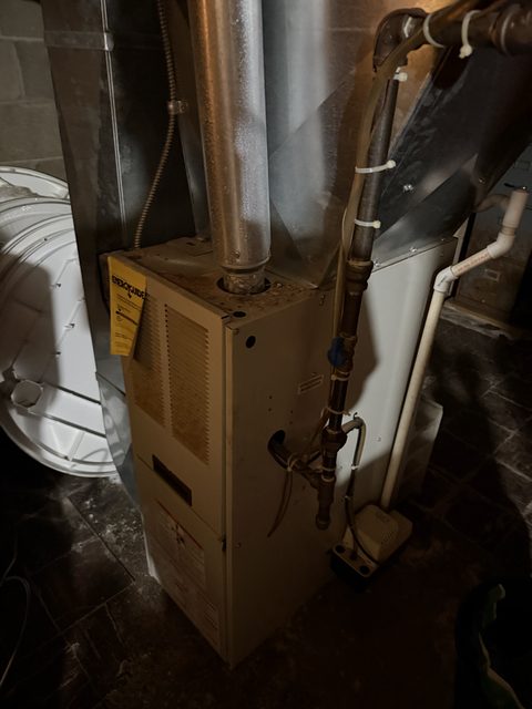 Gas furnace in a basement with its vent pipe, gas line and condensate pump