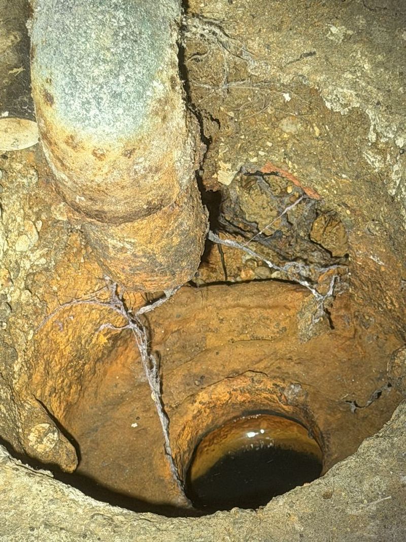 Old corroded cast iron pipe exposed in a basement floor during a pipe repair