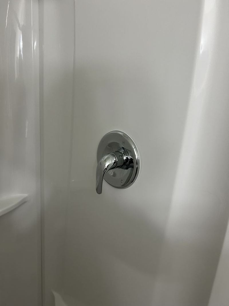 New chrome shower valve trim on a shower wall