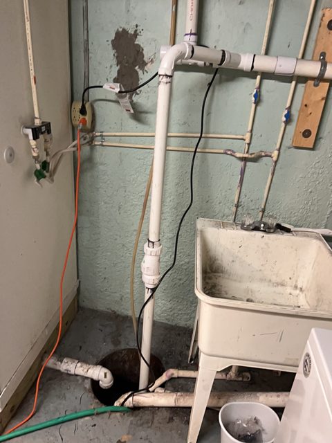 Sump pump pit with its discharge piping in a basement