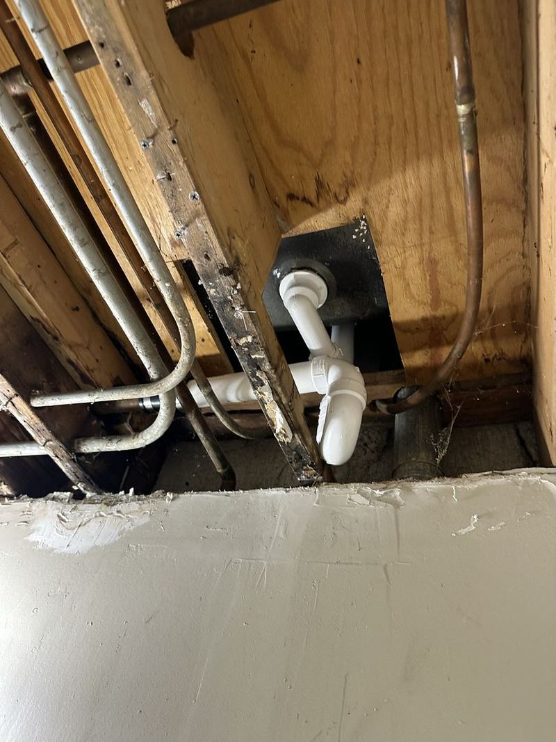 Tub drain and P-trap piping seen through an open ceiling