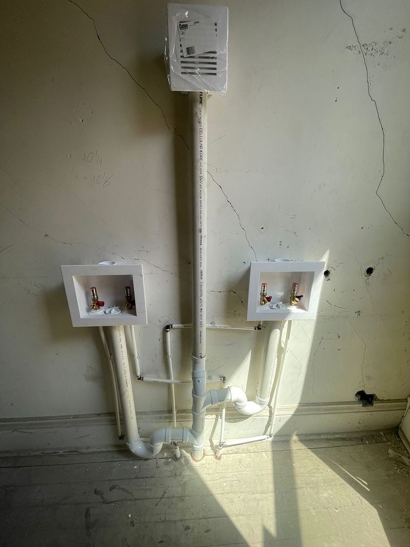 Washing machine boxes with water supplies and drain standpipes installed on a wall