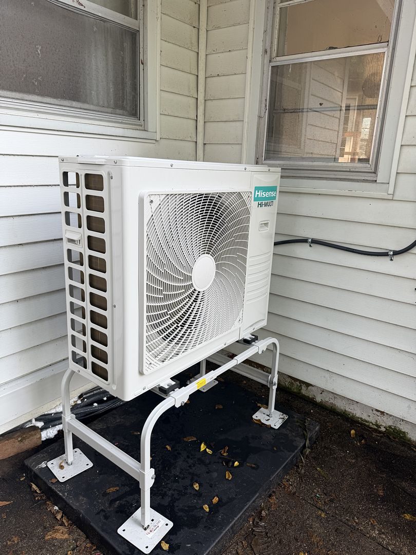 Mini split outdoor unit on a stand beside the home