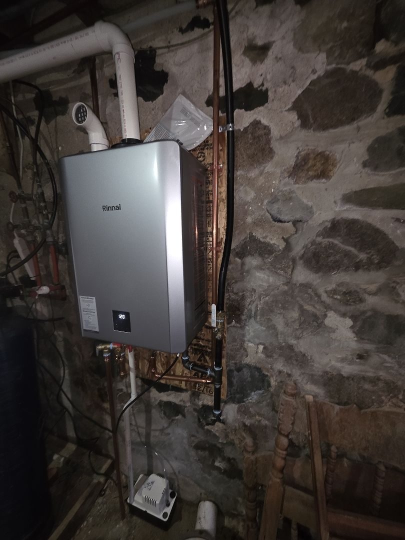 Side view of the Rinnai tankless water heater and its piping on the basement wall
